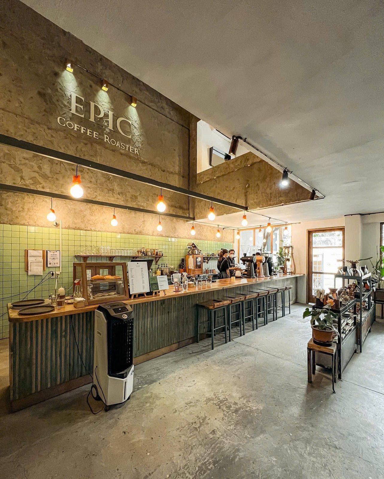 Quầy bar của quán, thắp đèn dây ấm áp dưới chữ EPIC COFFEE ROASTER trên tường